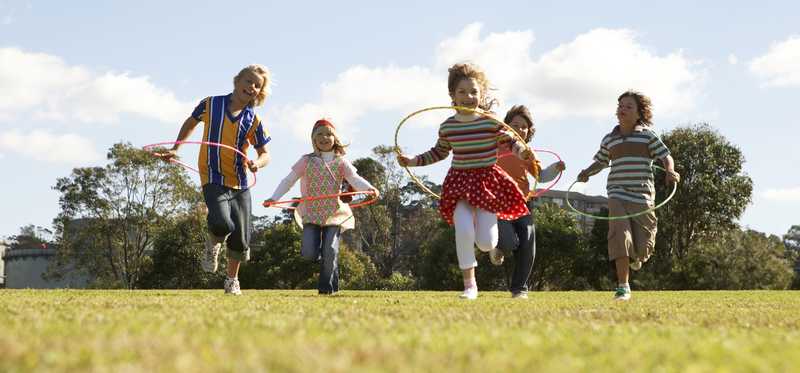 Children Hula-Hooping in a grassy field.