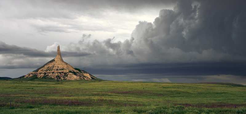 Chimney Rock in Nebraska with storm clouds in the distance.
