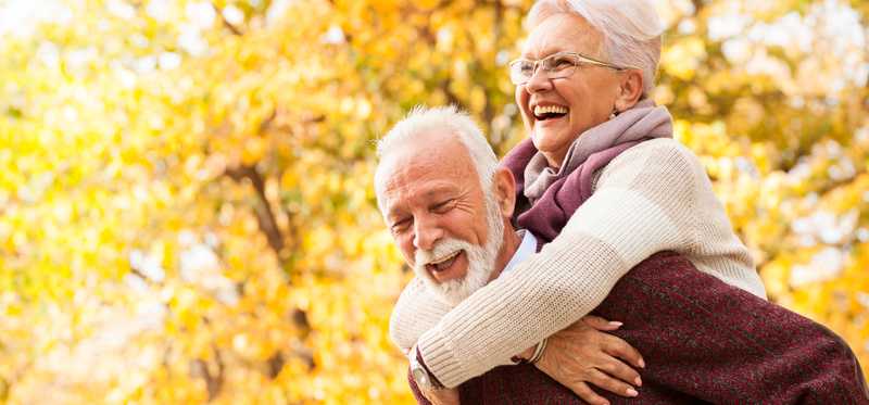Happy people doing piggyback ride in autumn.