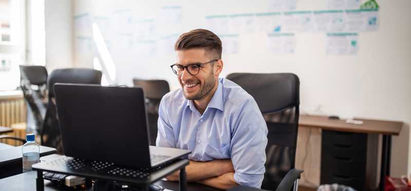 Person sitting in office and smiling while looking at computer screen.