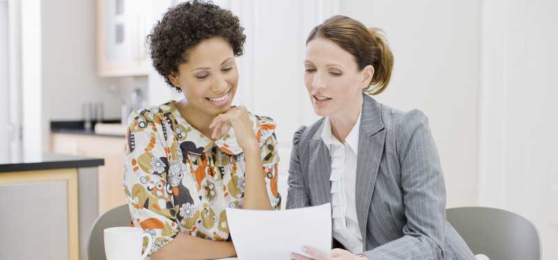Two men sitting at table while reviewing documents