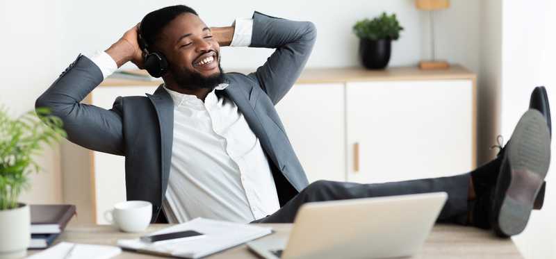 Person looking at computer on desk while leaning back and smiling.