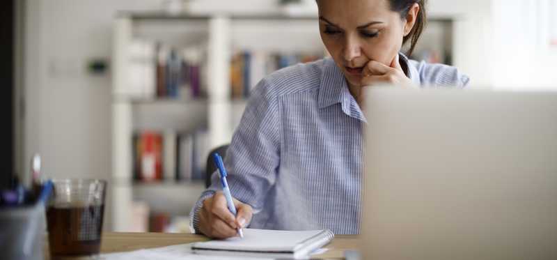 Woman sitting at table with computer and paying bills