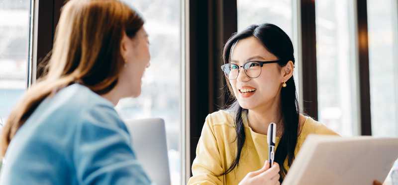 Two people sit at table and discuss document.