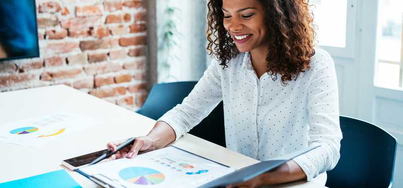 Person sitting in office while looking at binder displaying graphs.