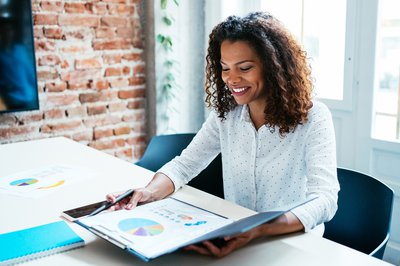 Person sitting in office while looking at binder displaying graphs.