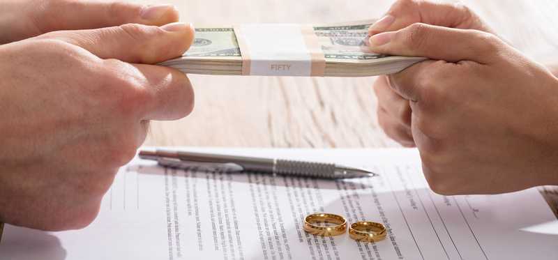 Two sets of hands fighting over money over divorce papers.