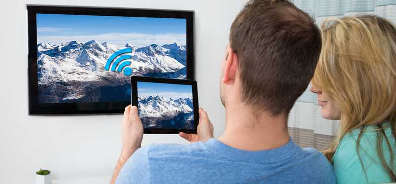Couple holding tablet watching TV.