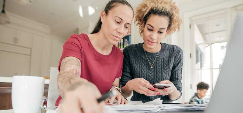 Two people looking at documents and smartphone.