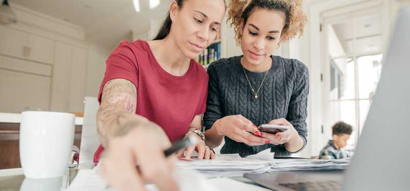 Two people looking at documents and smartphone.