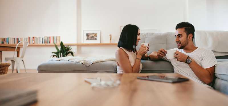 Young couple sits and talks while drinking coffee.