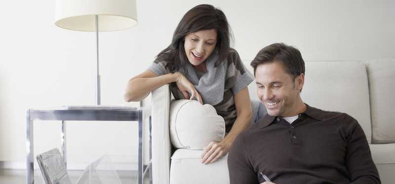 Two people using a laptop at home on the couch.