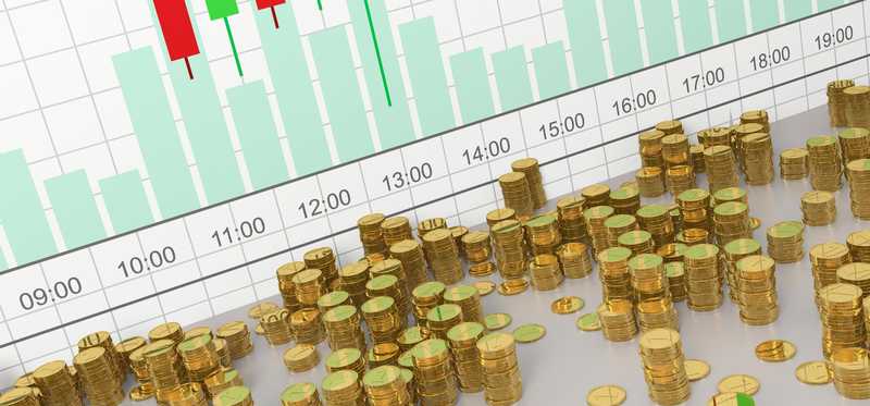 Stacks of physical crypto coins in front of a virtual currency price chart.