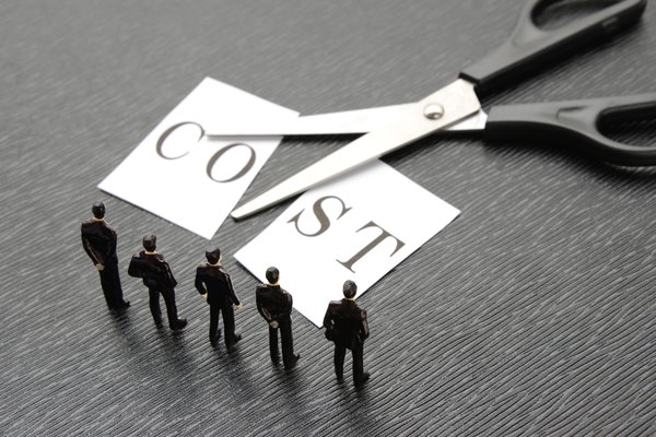 Scissors cutting a postcard that reads Cost in half.