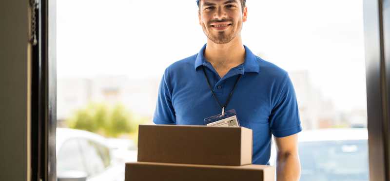 A delivery man with packages at the door.
