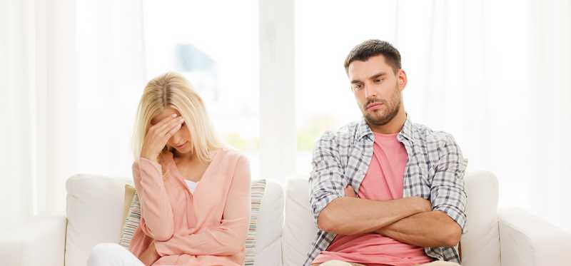 A couple looks sad on a couch.
