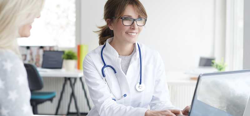 A doctor sits with a patient.