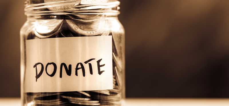 A donation jar with silver coins filled to the brim.
