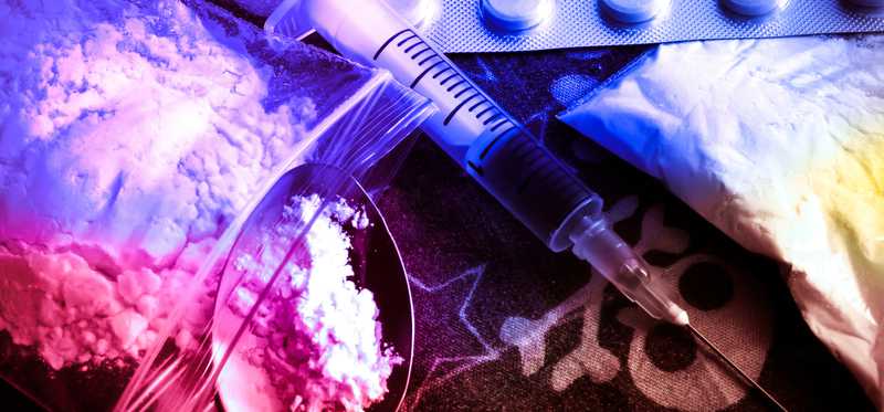 A pile of powder, pills, and a syringe.