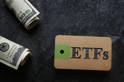 A tag with the acronym ETFs written on it with $100 bills nearby.