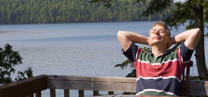 Man relaxing on a patio by the lake.
