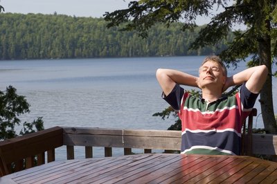 Person relaxing on a deck by a lake.