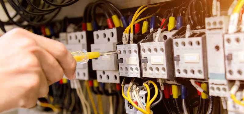 A person works on an electrical box.