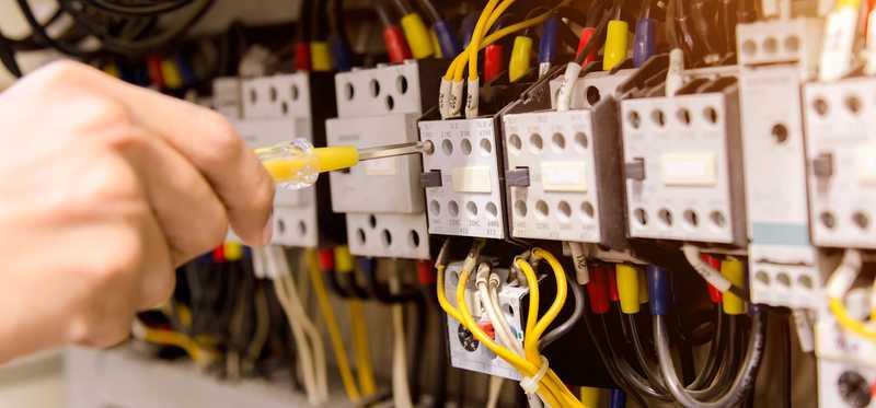 A person works on an electrical box.