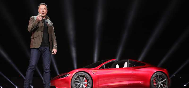 Elon Musk on stage by the Tesla Roadster.