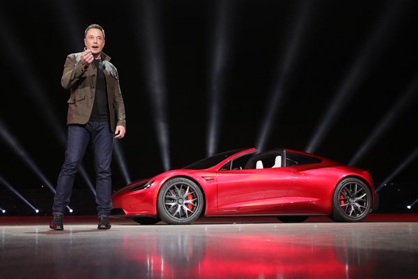 Elon Musk on stage by the Tesla Roadster.