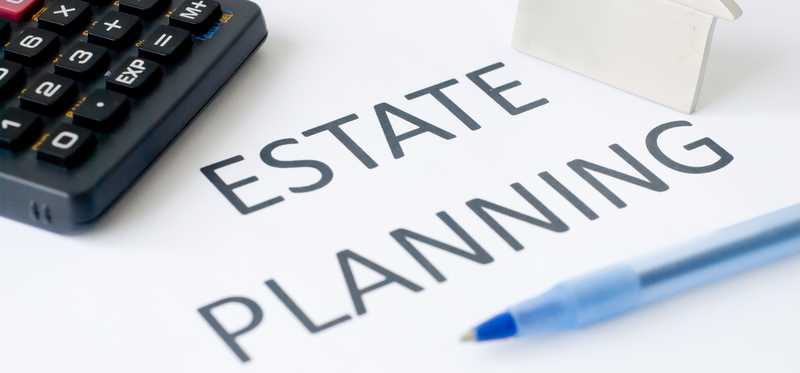 Estate Planning written on paper with calculator and small metal house on top.