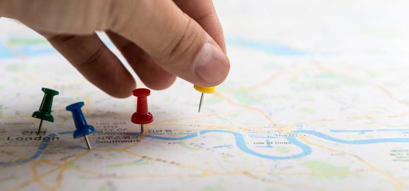 Road map with colored pushpins being inserted