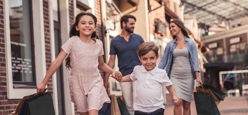 Family carrying shopping bags through shopping center.