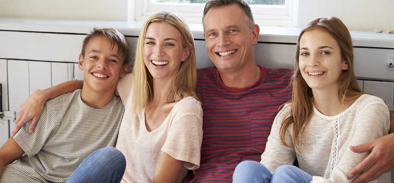 Family sits together, smiling.