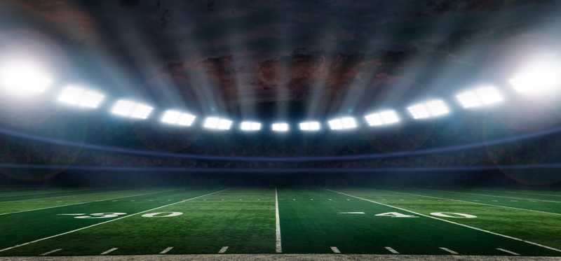 A football field with stadium lights on.