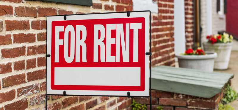 For rent sign in front of a brick residential building.
