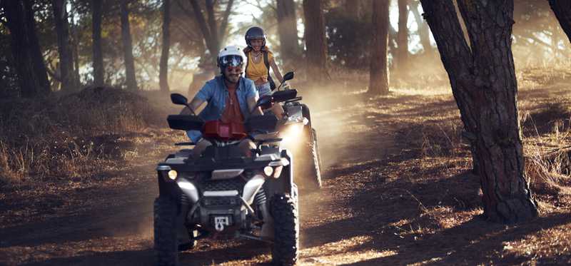 People riding ATVs on a forest trail.