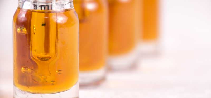 Four vials of cannabis oils lined up on a counter.