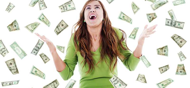 Young girl raises her hands in the air as money falls down around her.