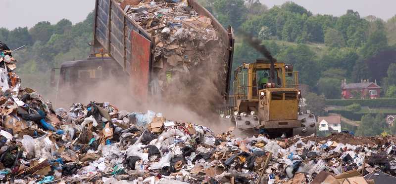 Garbage truck unloading trash at a dump.