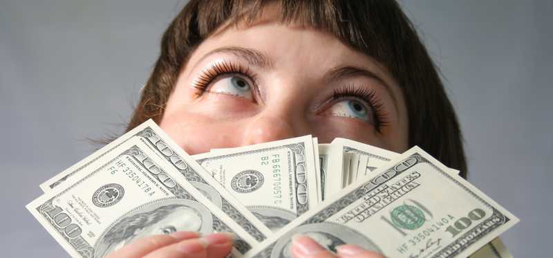 Woman smelling hundred dollar bills.