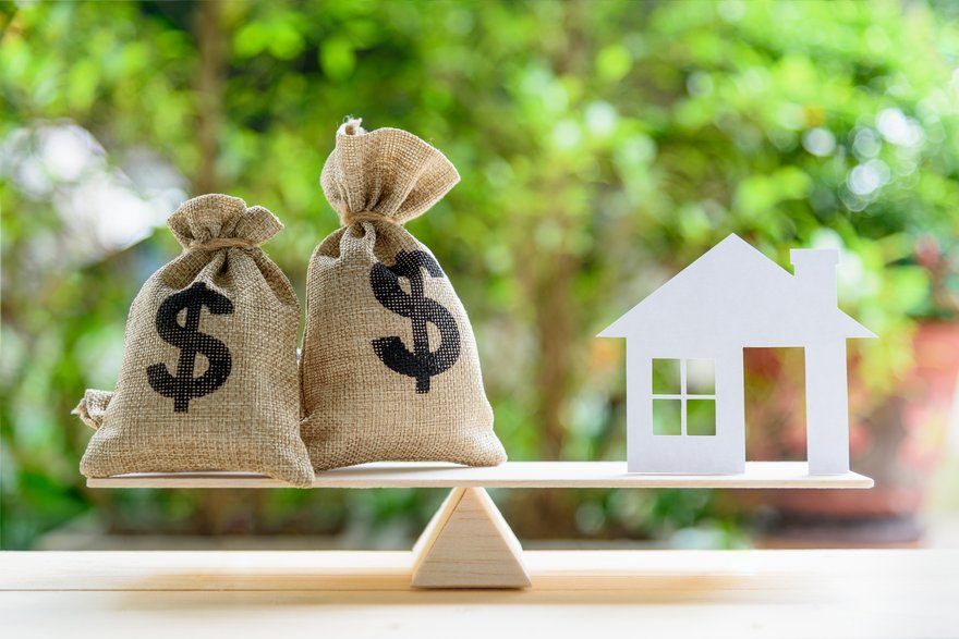 Balance beam with sacks of cash on one side and a home on the other.