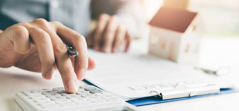 Person types on calculator while working on document.