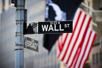 Photo of the Wall Street street sign with American flag in the background.