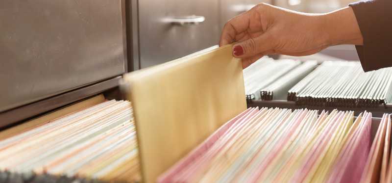 Person looking through filing cabinet.