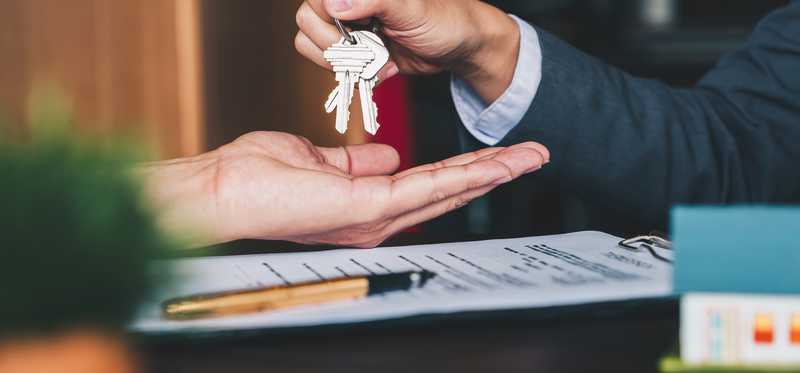 Person handing keys to buyer with contract.