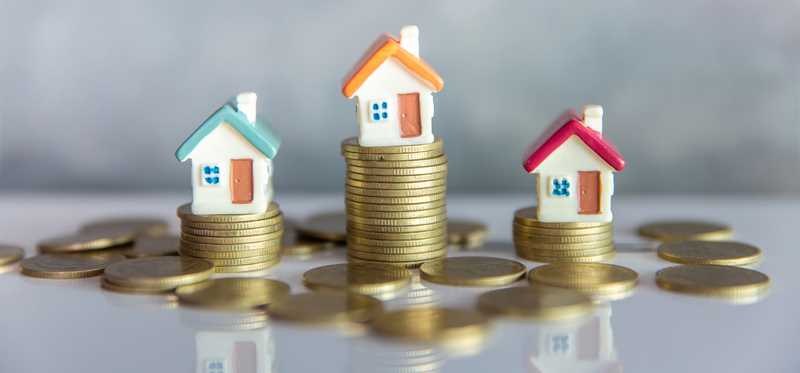 Miniature houses on top of stacks of coins.