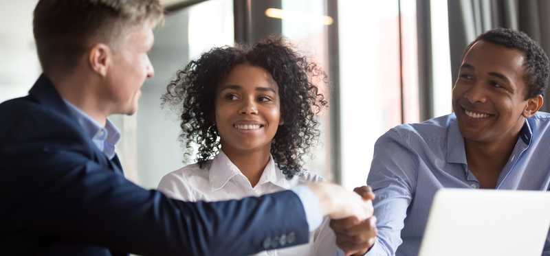 Happy clients shake hands with advisor.