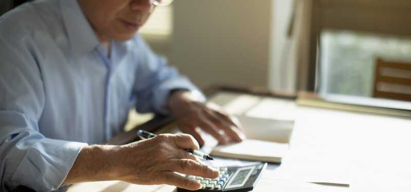 Person sitting at table and calculating finances.