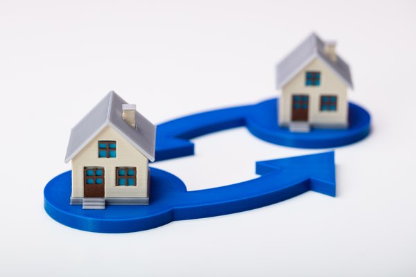 Two model houses sitting atop blue arrows pointing in a circular exchange motion.